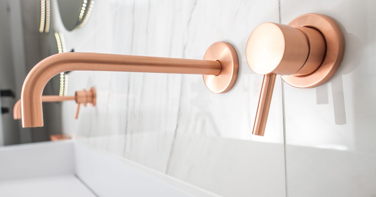 Minimalist copper faucet mounted on a marble wall