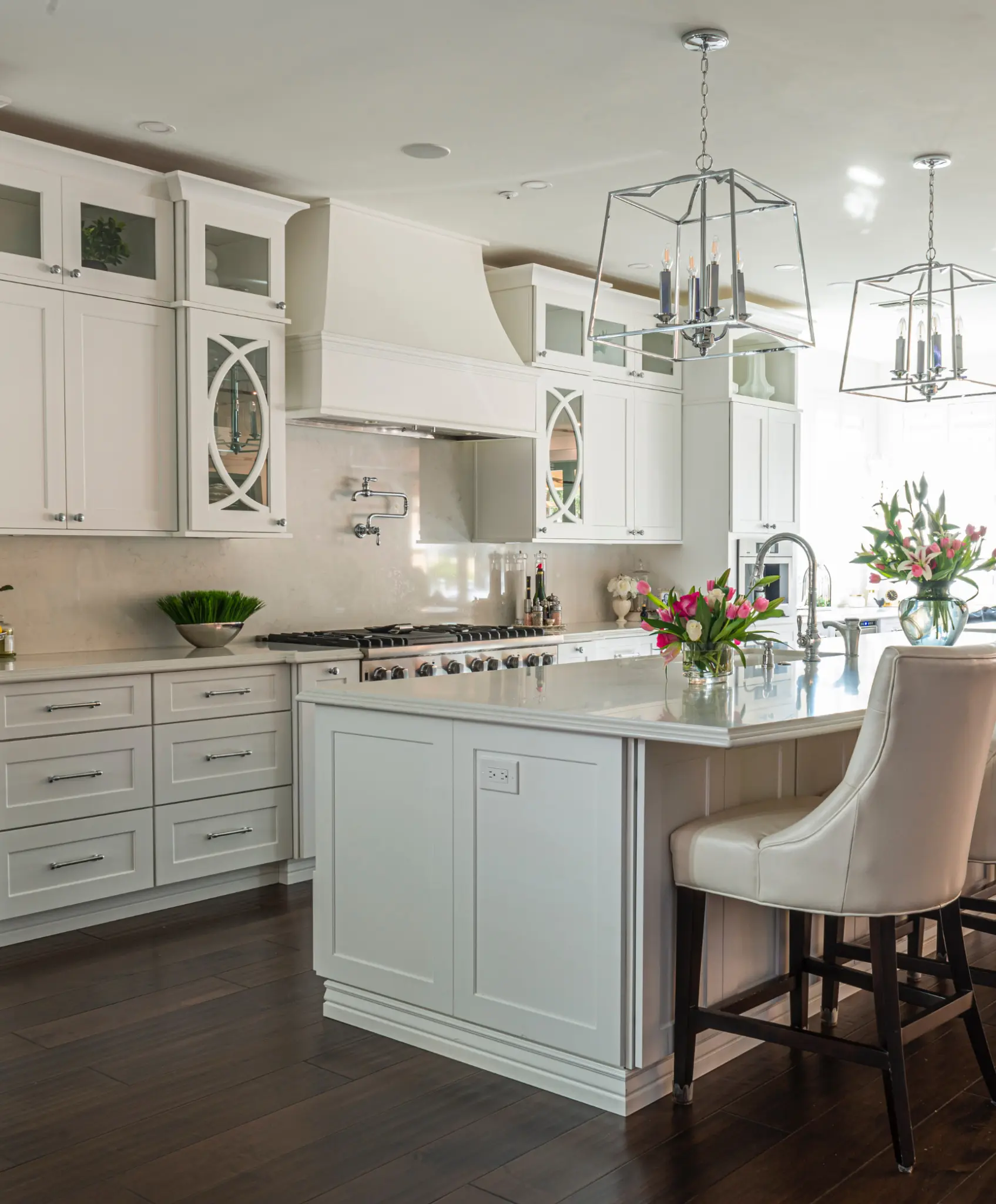 Elegant white kitchen with glass cabinet doors and island seating