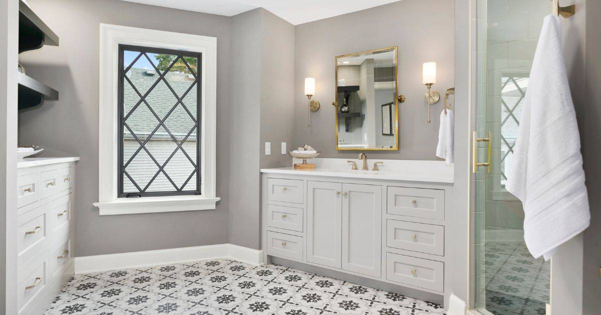 Elegant bathroom with a white vanity, patterned tile floor, and gold accents