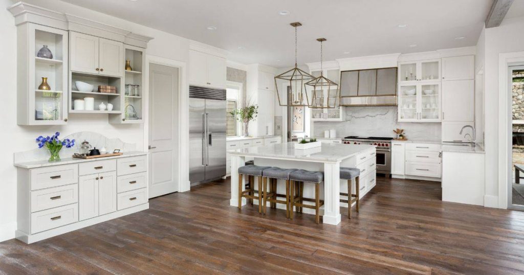 Elegant kitchen with a large island, gold pendant lights, and white cabinetry