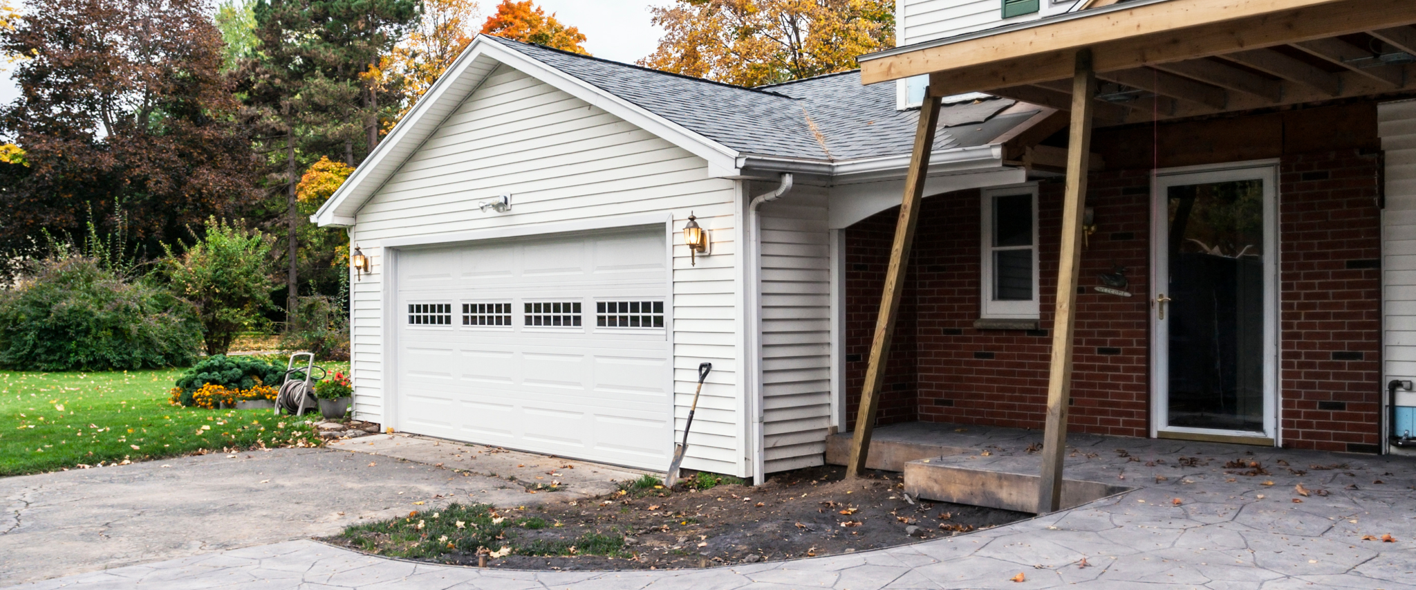 Home exterior featuring a white garage addition, brick siding, and a driveway under construction.