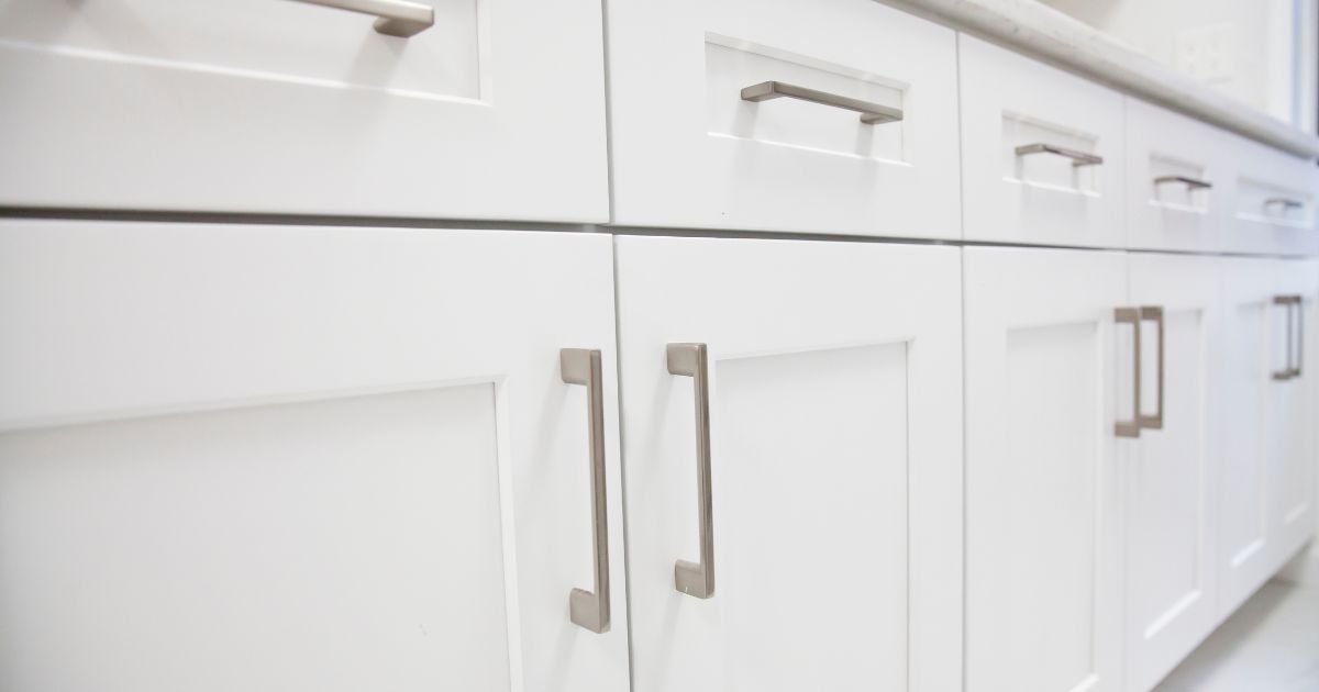 A close-up of white kitchen cabinets with modern silver handles.