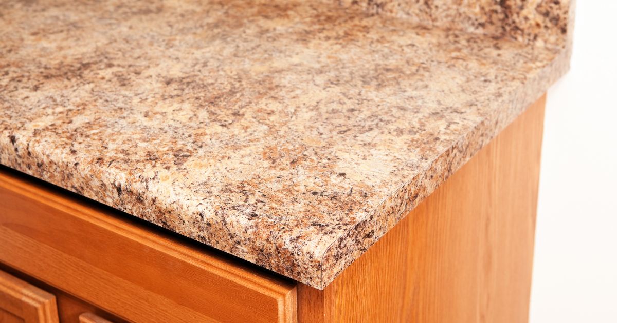 A close-up of a brown speckled laminate countertop with a wooden cabinet underneath.