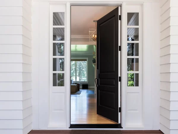 Partially open black front door with glass panels, revealing a bright interior.